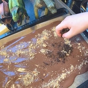 Adding the chocolate biscuit dirt to make the chocolate dinosaur bark