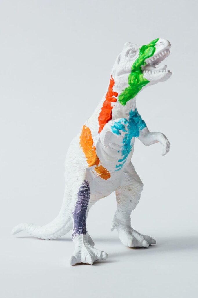 An artsy dinosaur cake topper, painted white and then splashed with bright coloured paint